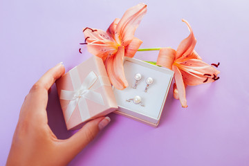 Woman opens gift box with set of pearl jewellery and flowers. Earrings and ring with lily. Gift...