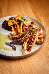 Closeup of cooked octopus tentacles with vegetables and sauce.