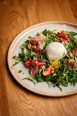 Closeup of a prosciutto salads with fresh mozzarella cheese and strawberries.
