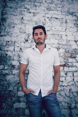 handsome young man in front of white brick wall