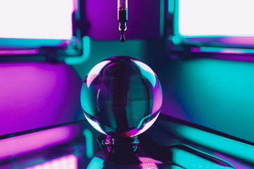 Red drops on glass ball in colorful lighting