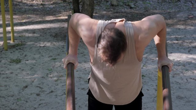 calisthenics street workout an athlete doing chest exersice on bars outdoors