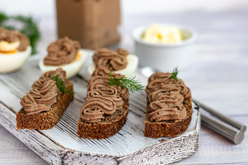 Fresh homemade chicken liver pate with carrots, onions and butter. Garnished with a sprig of dill. Lubricated on bread. On white background.