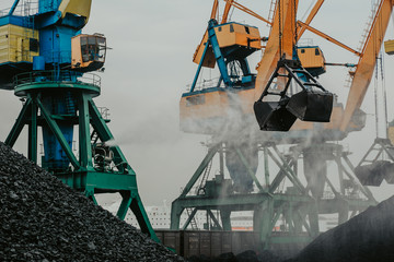 port cranes are loading coal into a transporting train.port cranes are loading coal into a...