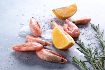 Seafood. Raw pink prawns shrimp with lemon, ice, rosemary and large sea salt on a light grey background. Background image, copy space