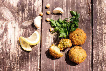 falafel balls from hummus on the wooden table with design lemon and parsley and garlic with cilantro Vegetarian dish -  from spiced chickpeas food flat lay 