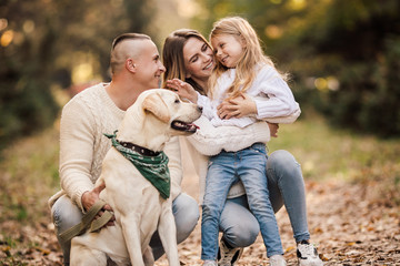 Happy beautiful family with dog labrador is having fun together walking the in park.