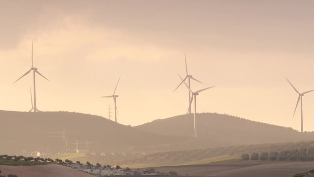 Wind turbines on hills at sunset light. Power generator farm for renewable electric energy production near Ardales, province Malaga, Andalusia Spain