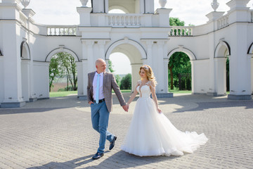 The bride and groom go by the hand. The couple smiles at each other.