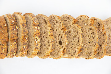 Fresh loaf with poppyseeds cutting on slices laying together. Sliced bread with seeds made of rye flour isolated on white background. Studio shot. Top view. Homemade bakery and nutrition concept