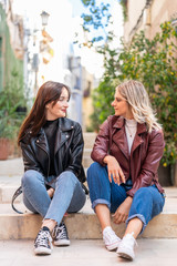 Fototapeta premium couple of attractive girls sitting on the street dressed in casual clothes.