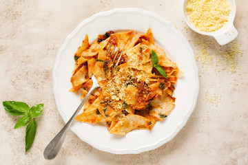 Pasta Maltagliati with classic tomato sauce, parmesan and basil on a rustic concrete light table background. Traditional Italian dish serving. Top view.