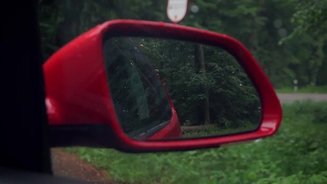 Ein Rotes Auto f&auml;hrt durch einen nebligen Wald mit Blick durch den Spiegel