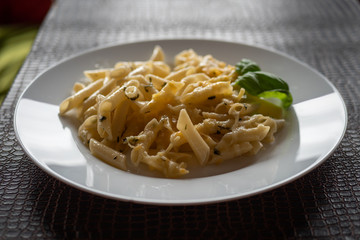 Macarrones al pesto en plato blanco.