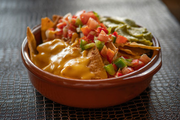 Nachos con queso, guacamole y pico de gallo en cazuela de barro.