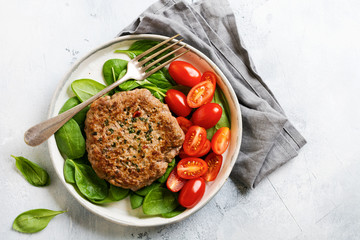 Grilled steak of beef with cherry tomatoes and spinach, garlic, seasonings, peppers and onions. Pleskavitsa – traditional Serbian dish. Top view.