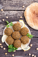 falafel balls from hummus the plate with design lemon and parsley, tomato, garlic on wooden table background with cilantro Vegetarian dish -  from spiced chickpeas food flat lay