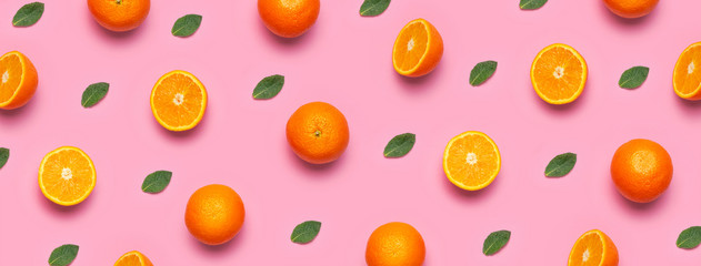 Fruit pattern, creative summer concept. Fresh juicy whole and sliced orange, mint leaves on pink background. Flat lay Top view. Minimalistic background with citrus fruits, vitamin C. Pop art design