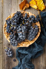 Vintage textured rattan plate and grape wine on old wooden background. Vintage Style. Top view.