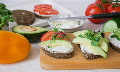 Sandwiches on a wooden board. A variety of sandwiches. Avocados, tomatoes, herbs. Top views. copyspace