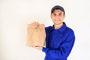 Young man courier is delivering a parcel in eco paper bag.