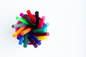 Set of multi-colored markers in a pink cup on white background. Top view.