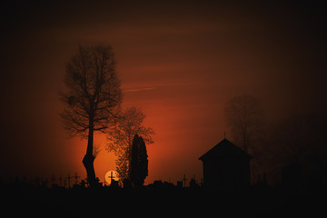 Krwawy wschód słońca nad starym cmentarzem