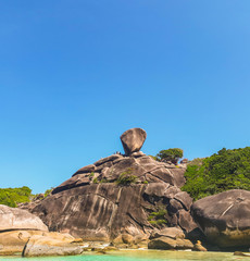 A high rock, on top of which there is a large stone that looks like a sail. Summer, sunny day, Similan islands.