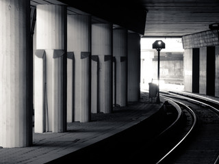 Black and white picture of the subway train tunnel with light in the end.