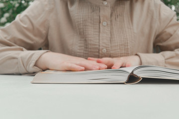Woman reading a book in the evening. Close-up of person reading a book at the table. 