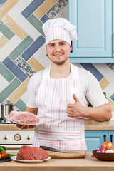 Young beautiful male chef presents food in the kitchen