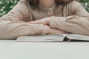 Woman reading a book in the evening. Close-up of person reading a book at the table. 