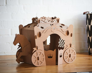 A horse and a carriage made of brown cardboard,where the horse is pulling the carriage.