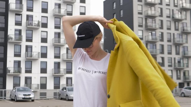 Young angry woman wearing feminist signs puts her coat on and croos her hands