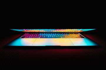Modern laptop with colored lights on the screen that illuminate the keyboard