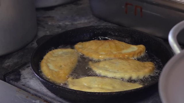 chef cooks ruddy flat patties with meat in boiling oil