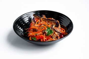 Hot Korean-style eggplant and tomato salad with sesame seeds and herbs on a white table. Asian...