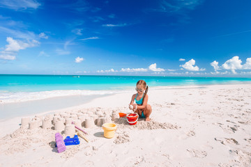 Fototapeta na wymiar Little girl at tropical white beach making sand castle