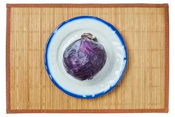 purple head of red cabbage on a white plate with a blue rim