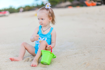 Little girl at tropical white beach making sand castle