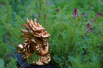 Dragon statuette in the green garden. Symbol of harmony and greatness.