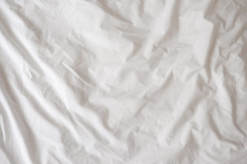 Background of white rumpled sheets. Bed linen with wrinkles in day light. Horizontal. Copy spase. Concept of rest, awakening, sleep, stay at home. For social media, blog