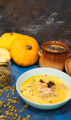 Tasty pumpkin cream soup with shrimps and basil leaves