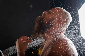 The bald guy takes a shower. A brutal man with a red beard is standing in the bathroom under a...