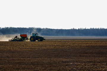 Fototapeta premium a large tractor with a seeder goes through the field.