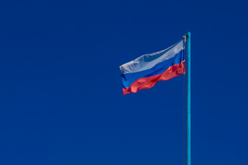 The flag of Russia is developing against a clear blue sky