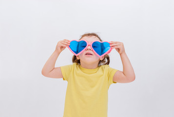 A blonde girl holds large funny glasses on a white background with her hands. Day of laughter. Children's game.