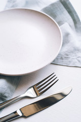 An empty plate and Cutlery on a white table. Top view.