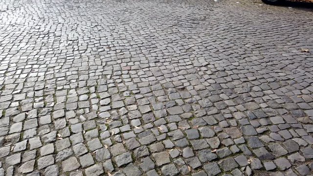 Cyclist riding on cobbled street, lower section