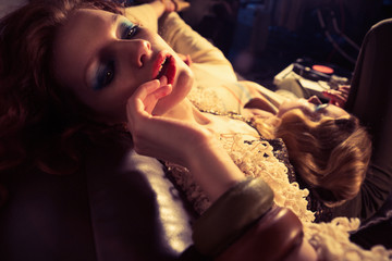 Beautiful woman model with red hair poses for the camera. Furnishings, clothing and design in the style of the 70s.